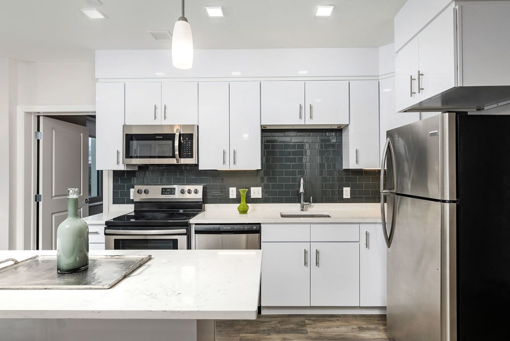 a white kitchen with stainless steel appliances and white cabinets