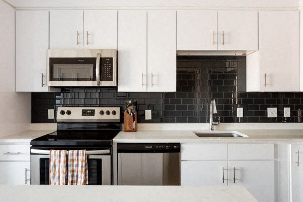 a kitchen with white cabinets and black and white appliances