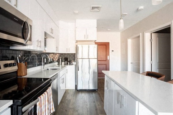 a kitchen with white cabinets and black appliances