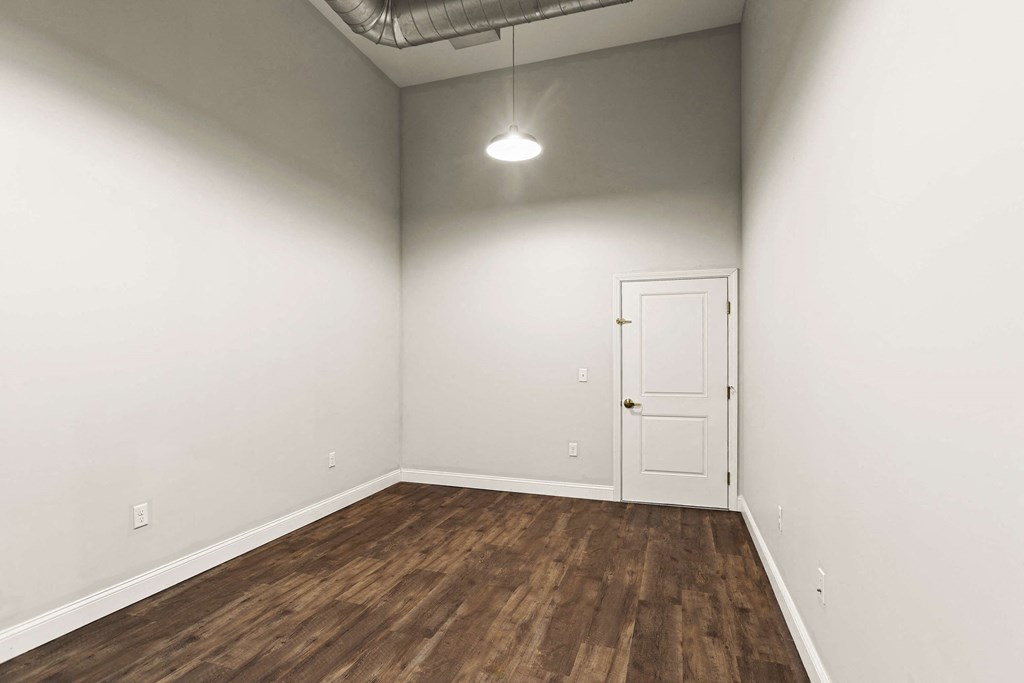 a room with white walls and wood floors and a white door