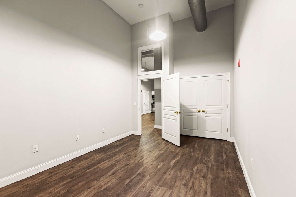 a living room with white walls and wood flooring and a white door