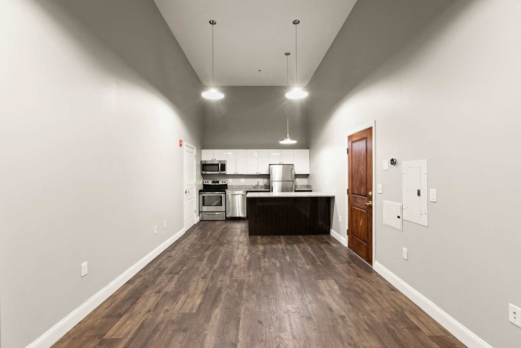 a kitchen and living room with white walls and wood floors