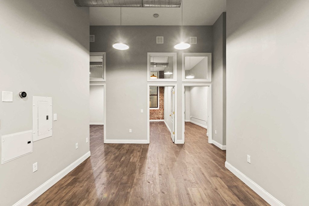the living room and dining room of an empty home with wood floors and white walls