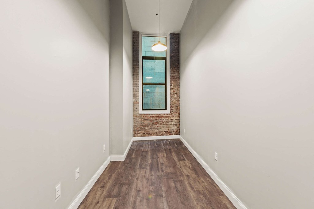 an empty room with white walls and a brick wall and a window