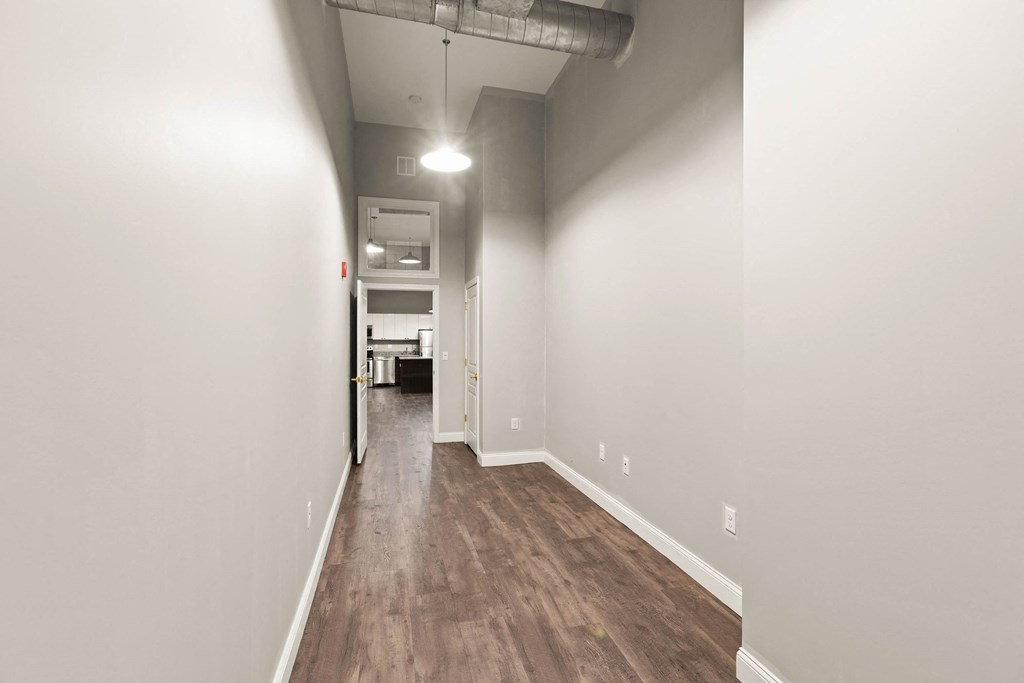 a long hallway with a wood floor and white walls