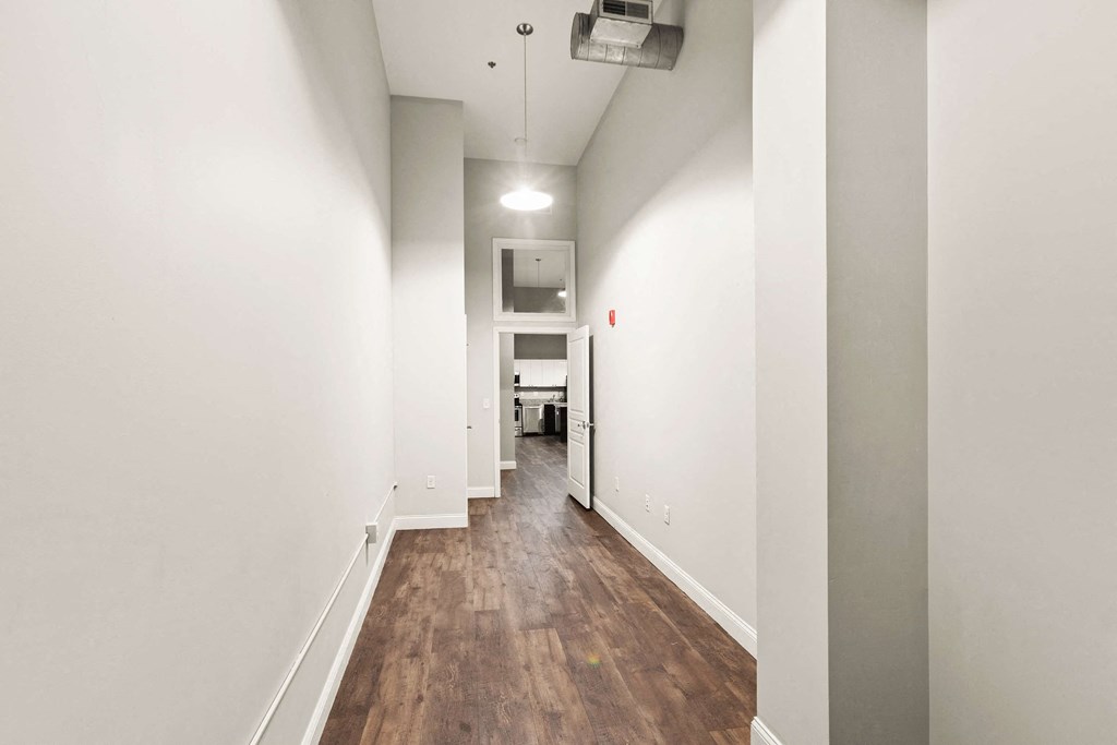 a long hallway with white walls and wood floors