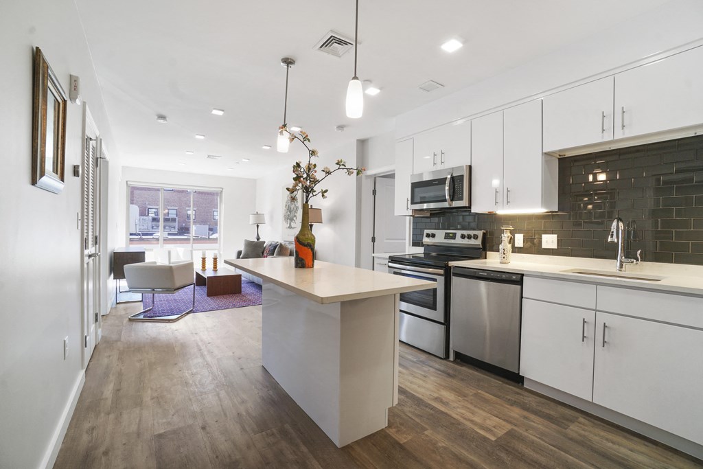 a kitchen with white cabinets and a white island with a vase of flowers on it