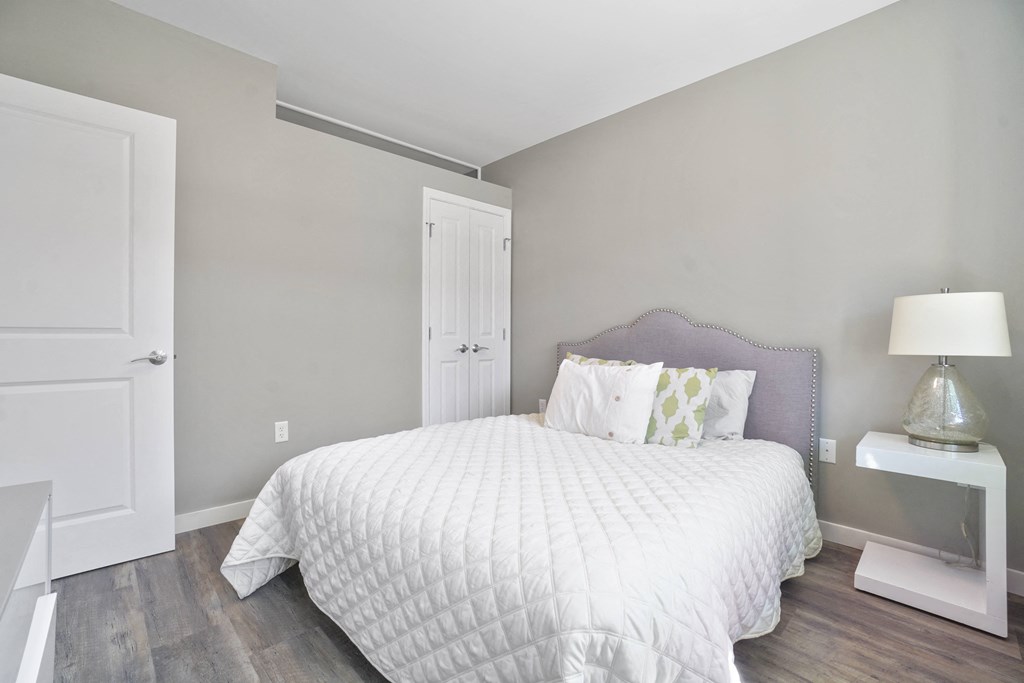 a bedroom with grey walls and a white bed with a white comforter