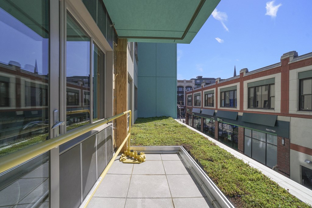 a view of a balcony with a grassy area and a train in the background