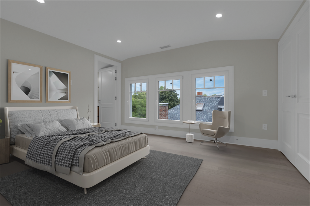 a bedroom with a bed and a chair in front of three windows