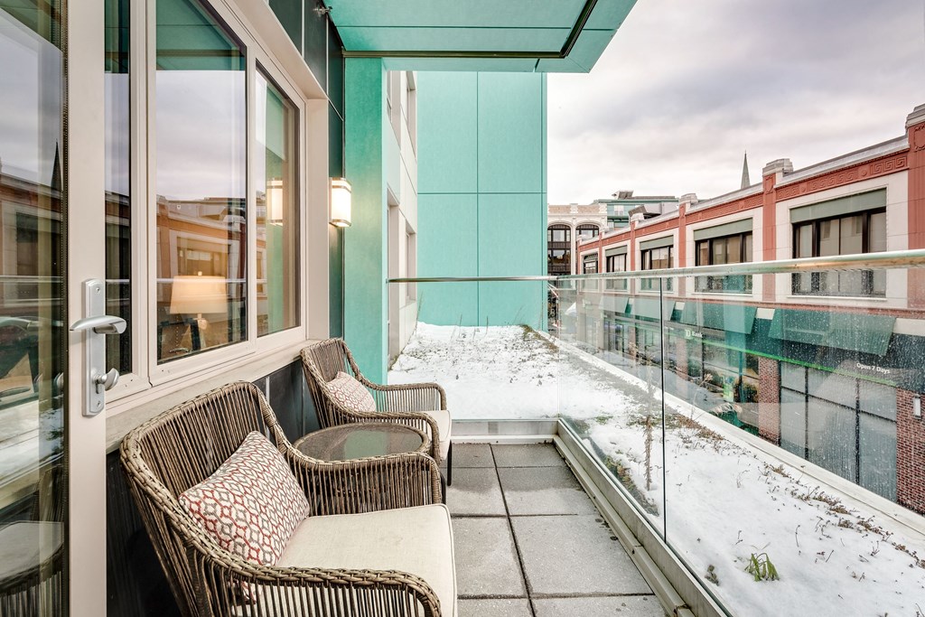 a balcony with wicker chairs and a view of the city