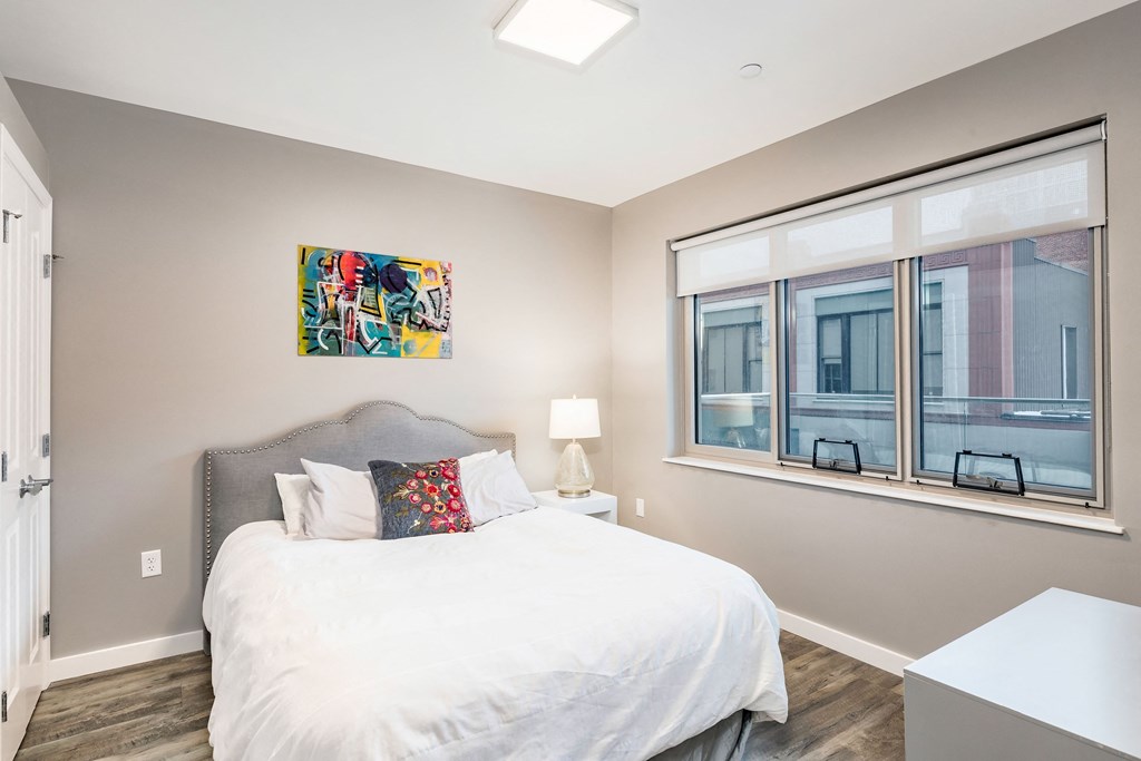 a bedroom with a large window and a white bed