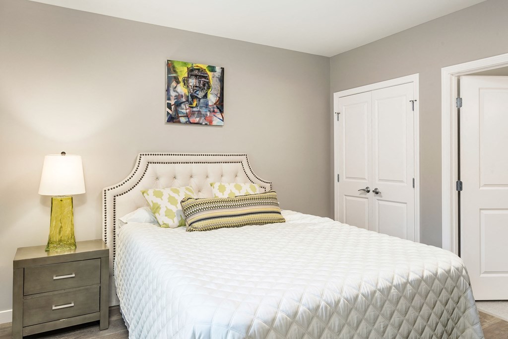 a bedroom with a white bed and a painting on the wall