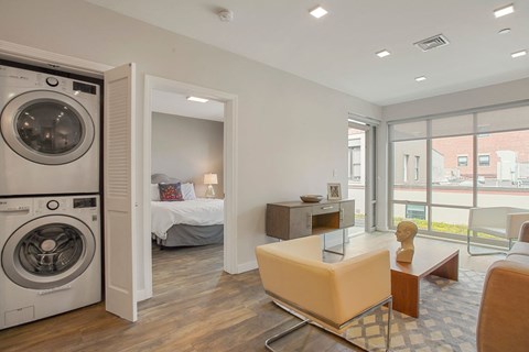 a living room with a washing machine and a bedroom with a bed