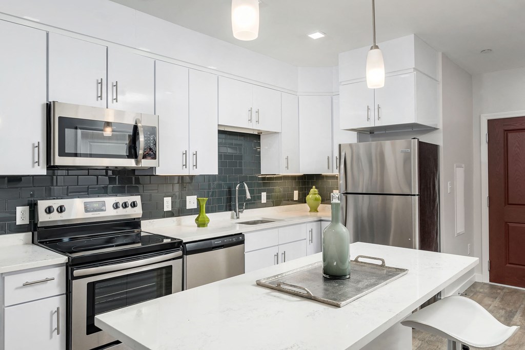 a white kitchen with stainless steel appliances and a white counter top