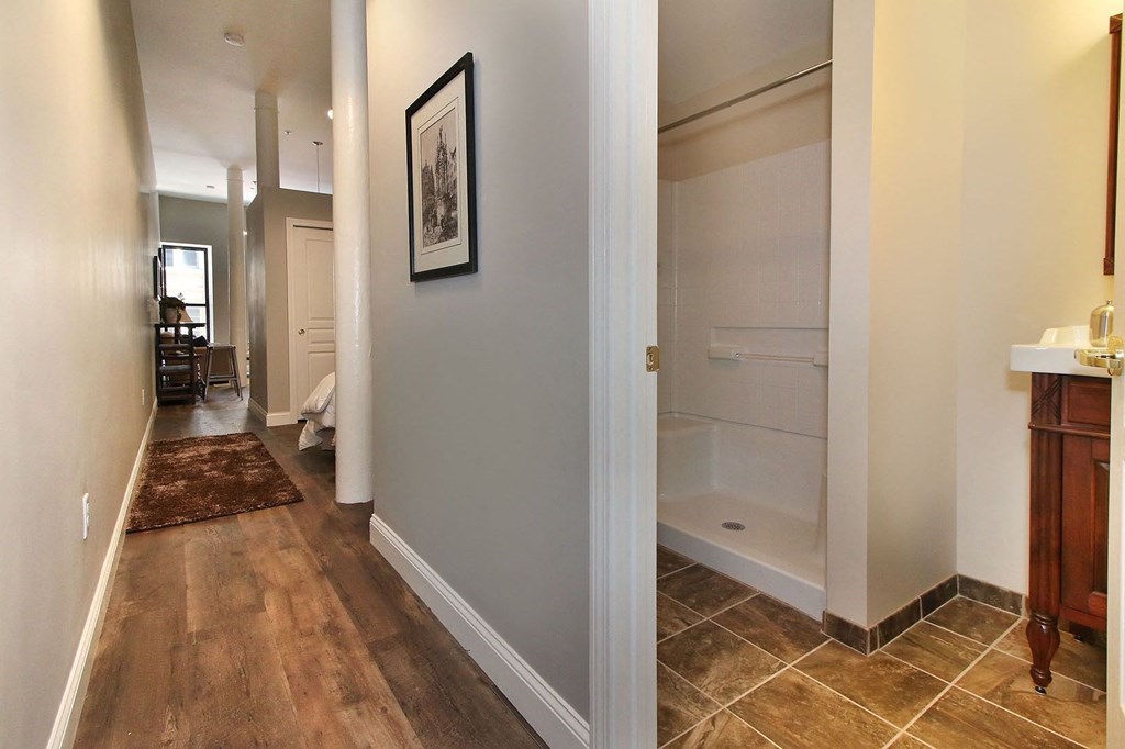 a bathroom with a tub and a sink and a hallway with a door open