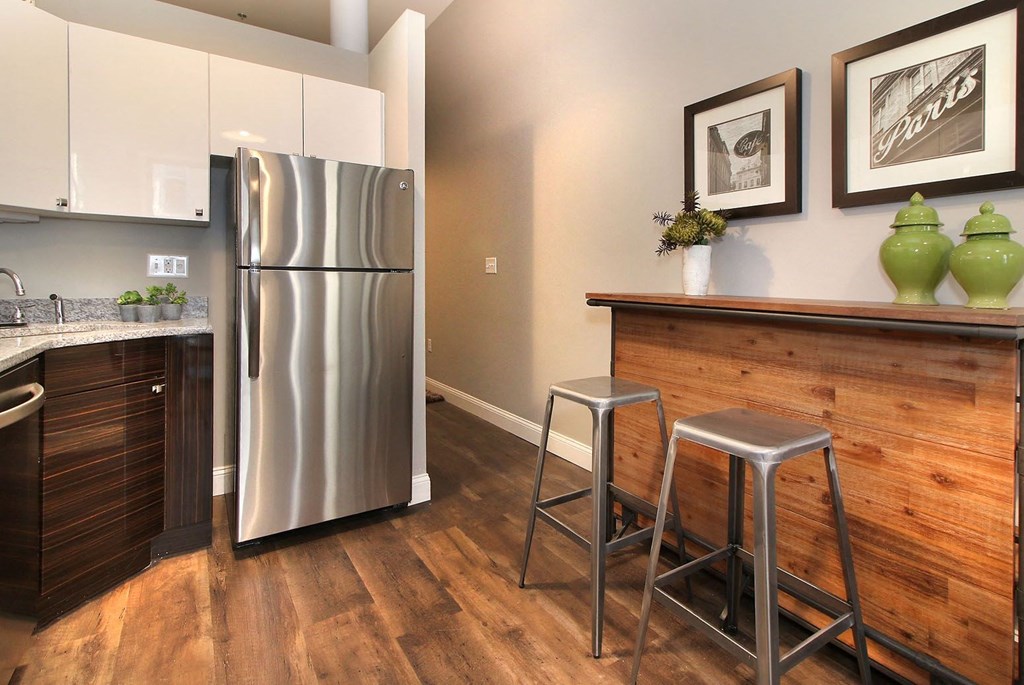 a kitchen with a stainless steel refrigerator and a bar with stools