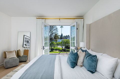 A bedroom with a large bed and a view of the outdoors through the window.