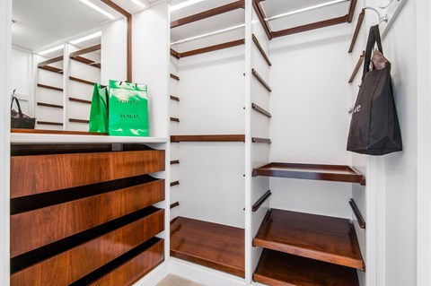 A black bag hangs on a hook in a white and wood storage space.