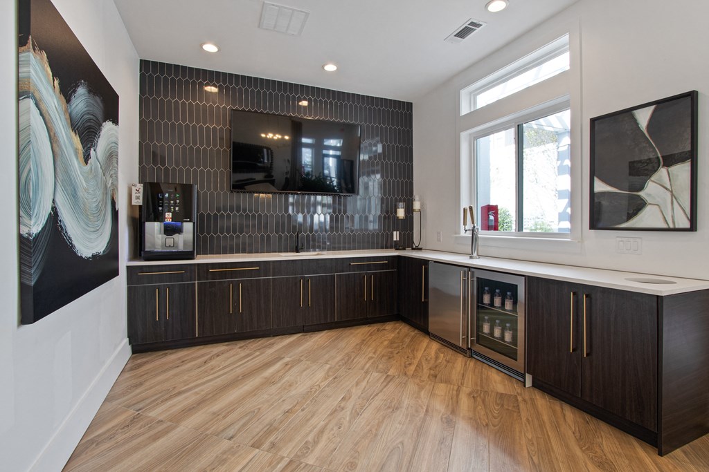 a kitchen with wood floors and black cabinets and a tv