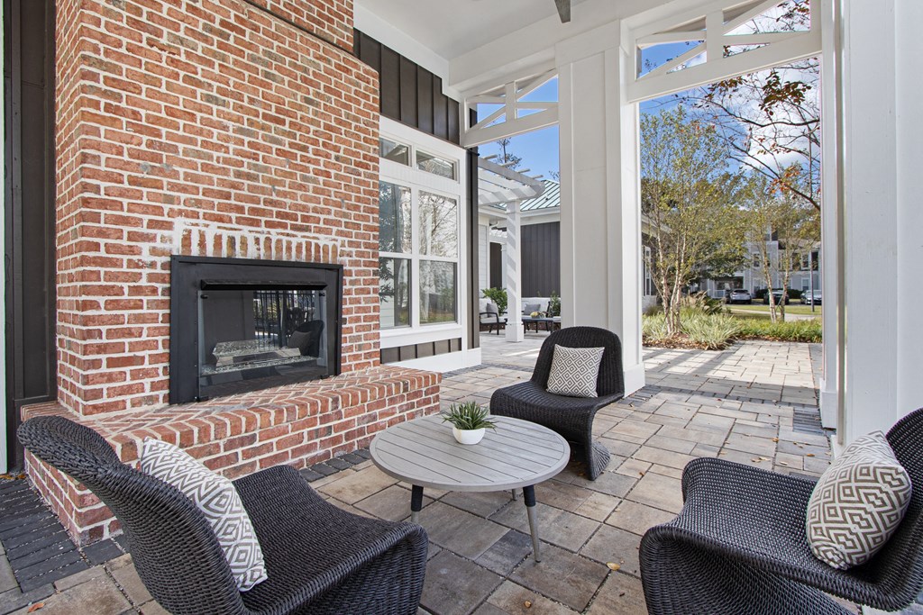 a patio with chairs and a brick fireplace