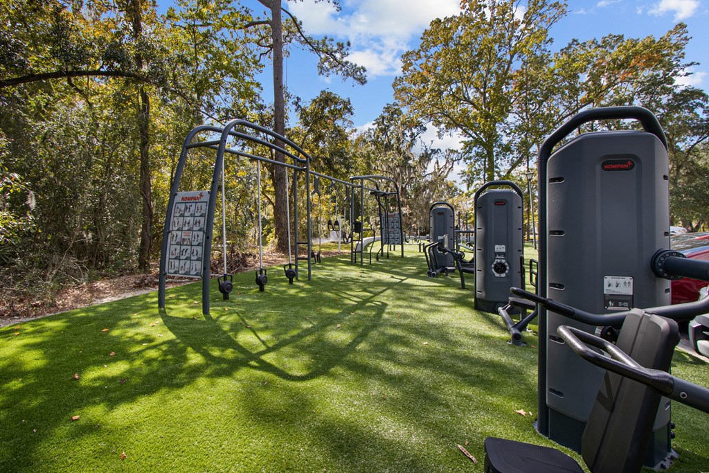a group of exercise equipment on the grass at a park