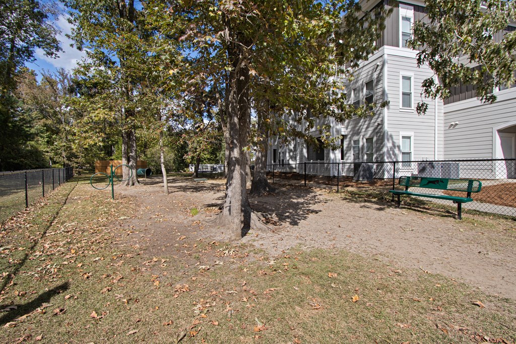 a park with a bench and trees in front of a building