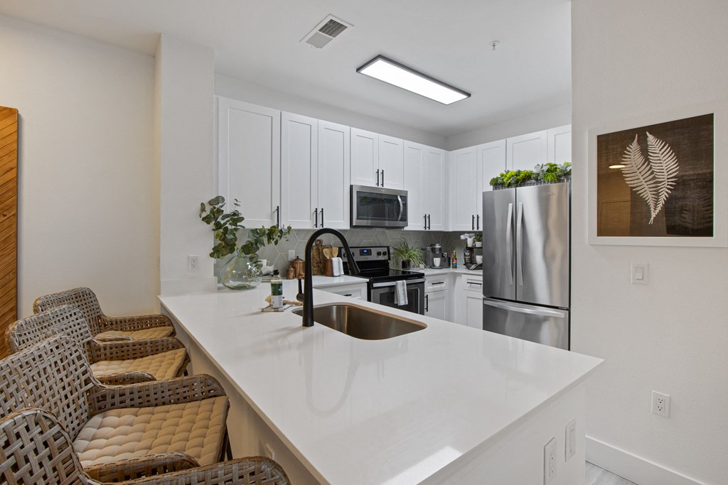 a kitchen with a white counter top and a stainless steel refrigerator