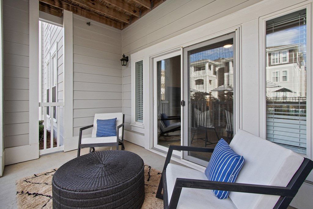 a covered porch with two chairs and a table