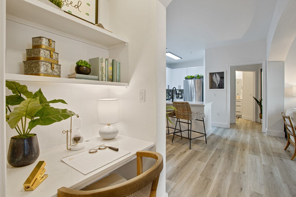 a home office with a desk and a living room with a kitchen