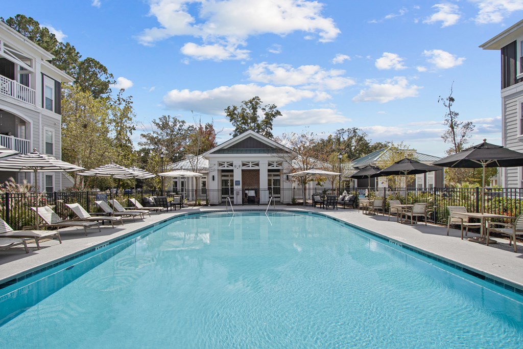 a swimming pool with chairs and umbrellas in front of a building