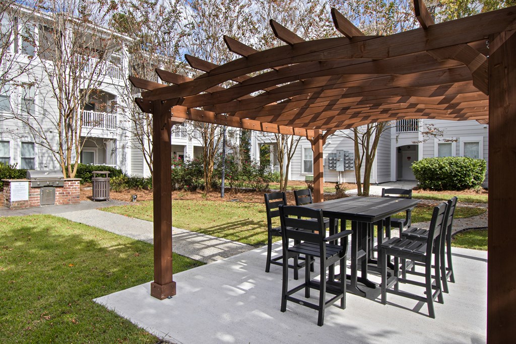 a patio with a table and chairs under a wooden pergola