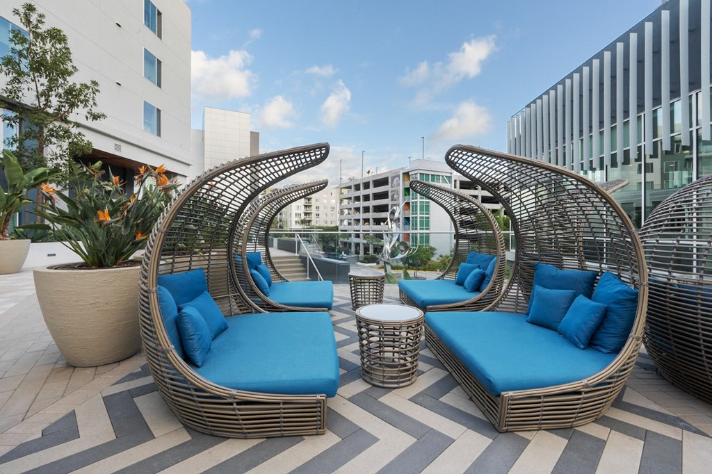 Two blue cushioned chairs and a table are on a patio.