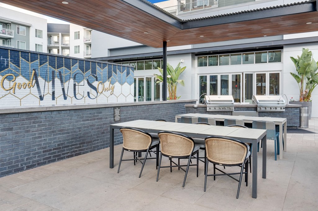 A patio with a table and chairs is in front of a building with a sign that says Good Vibes Only.
