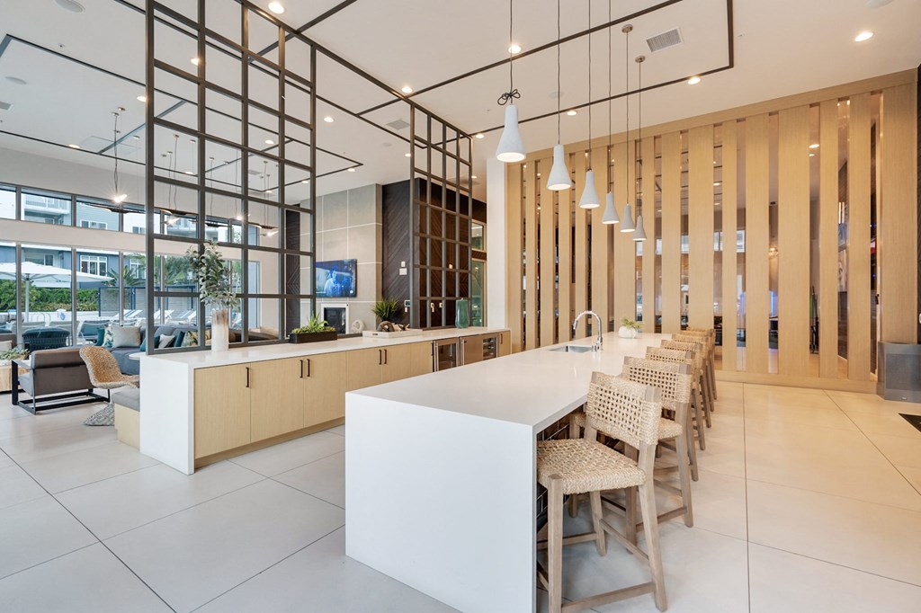 A modern kitchen with a white counter and chairs.