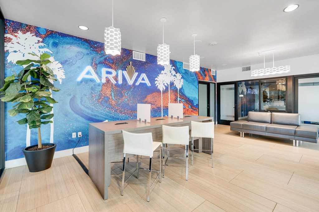 A white desk with chairs in front of a wall with the word ARIVA on it.