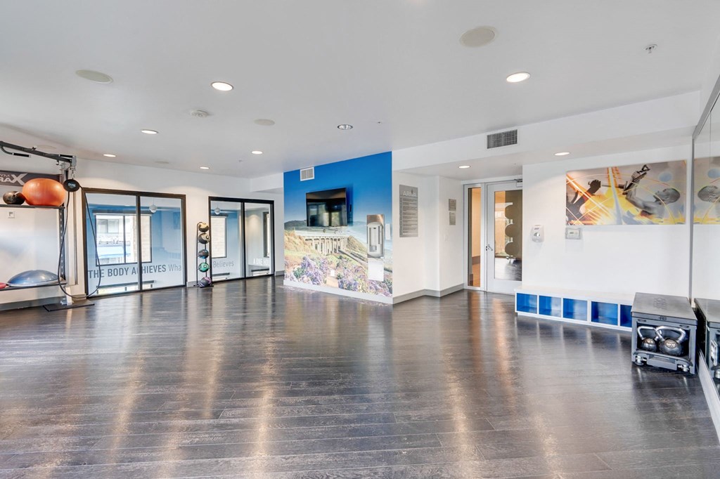 A spacious room with a wooden floor and a blue wall with a mural.
