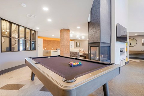 A pool table in a room with a brick wall and a fireplace.