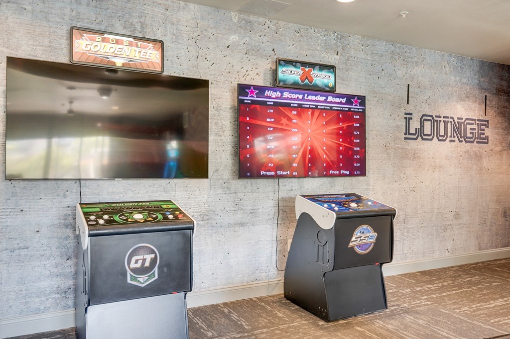 A lounge area with a high score leaderboard and two arcade machines.