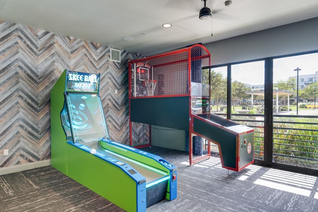 A room with a green and red arcade game and a basketball hoop.