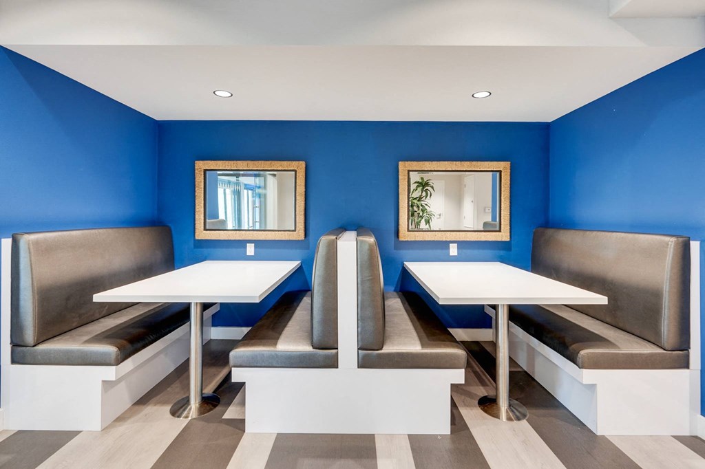 A blue and white restaurant with two tables and two benches.