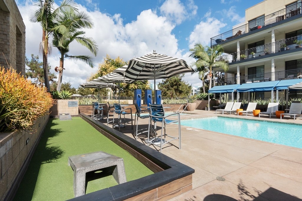 A pool area with a green pool mat and a striped umbrella.