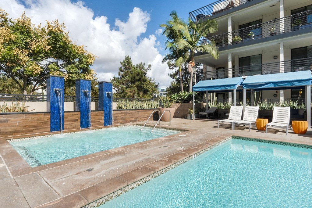 A swimming pool with a blue umbrella and chairs.