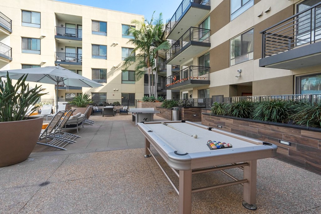 A pool table is in the middle of a courtyard surrounded by buildings.