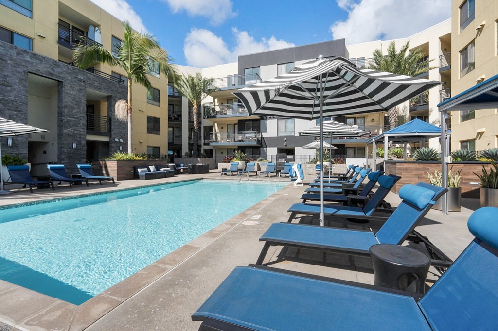A swimming pool surrounded by blue lounge chairs and umbrellas.