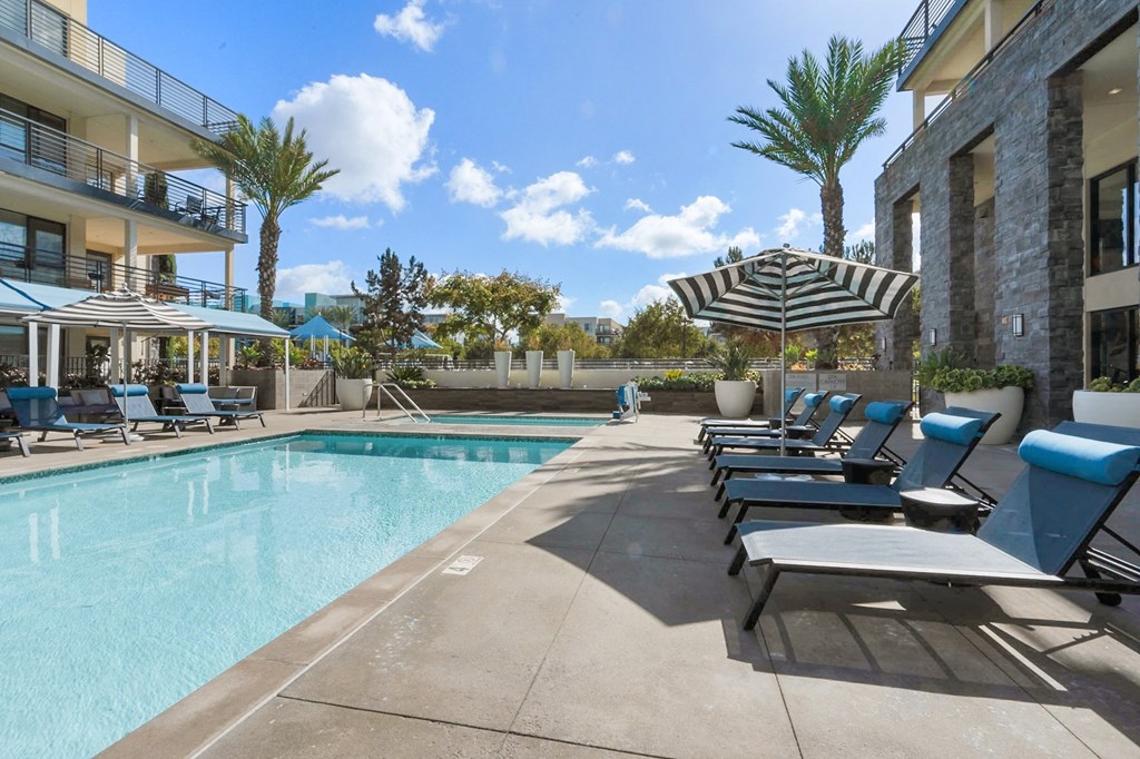 A pool area with sun loungers and a striped umbrella.