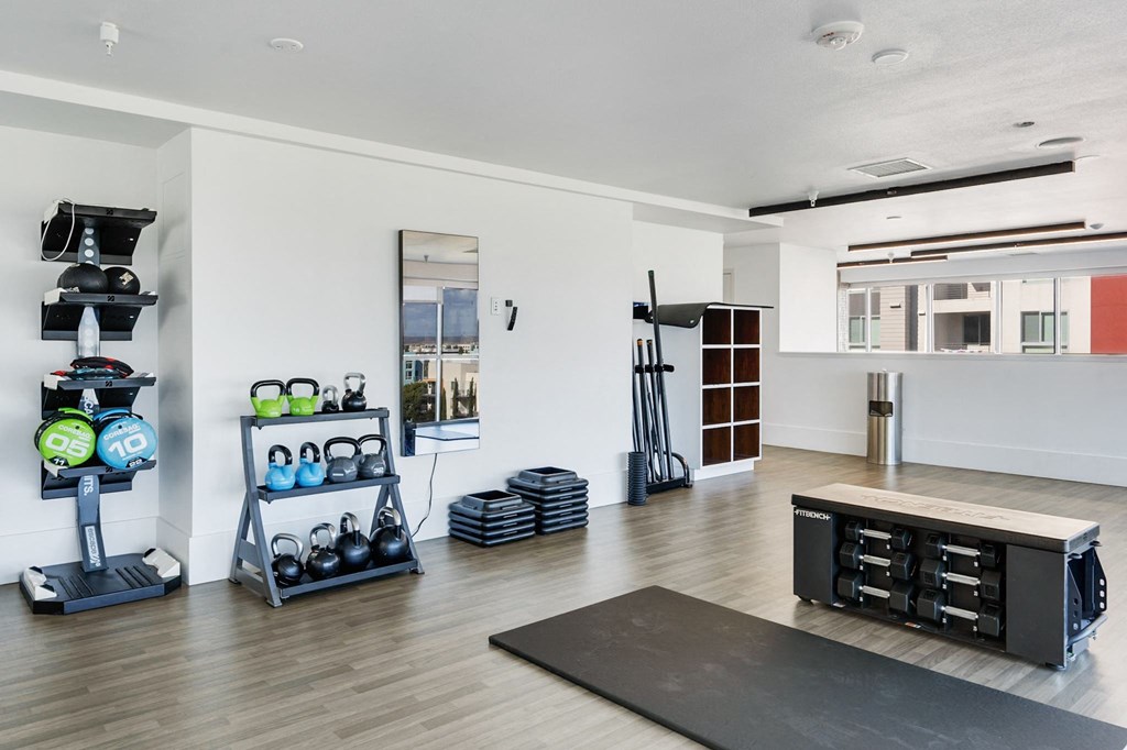 A home gym with a variety of equipment including a treadmill, weights, and a bench press.