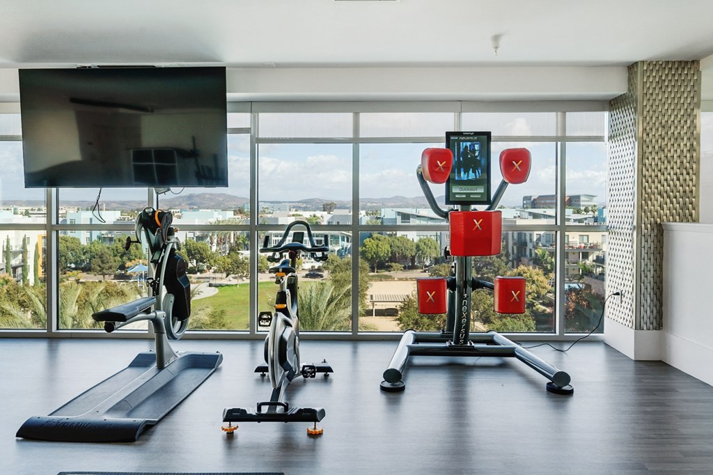 A home gym with a treadmill, exercise bike, and a weight lifting machine.