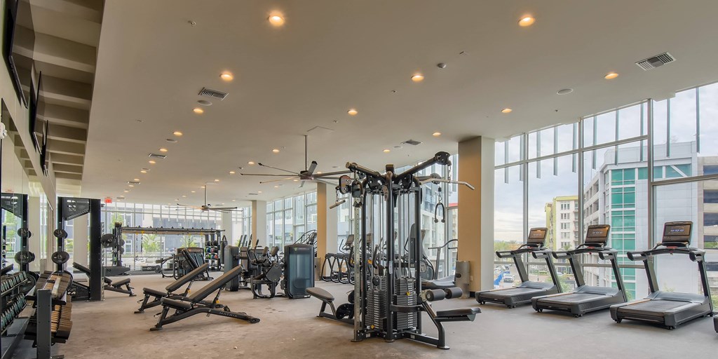 A gym with a variety of equipment including treadmills, weights, and exercise machines.