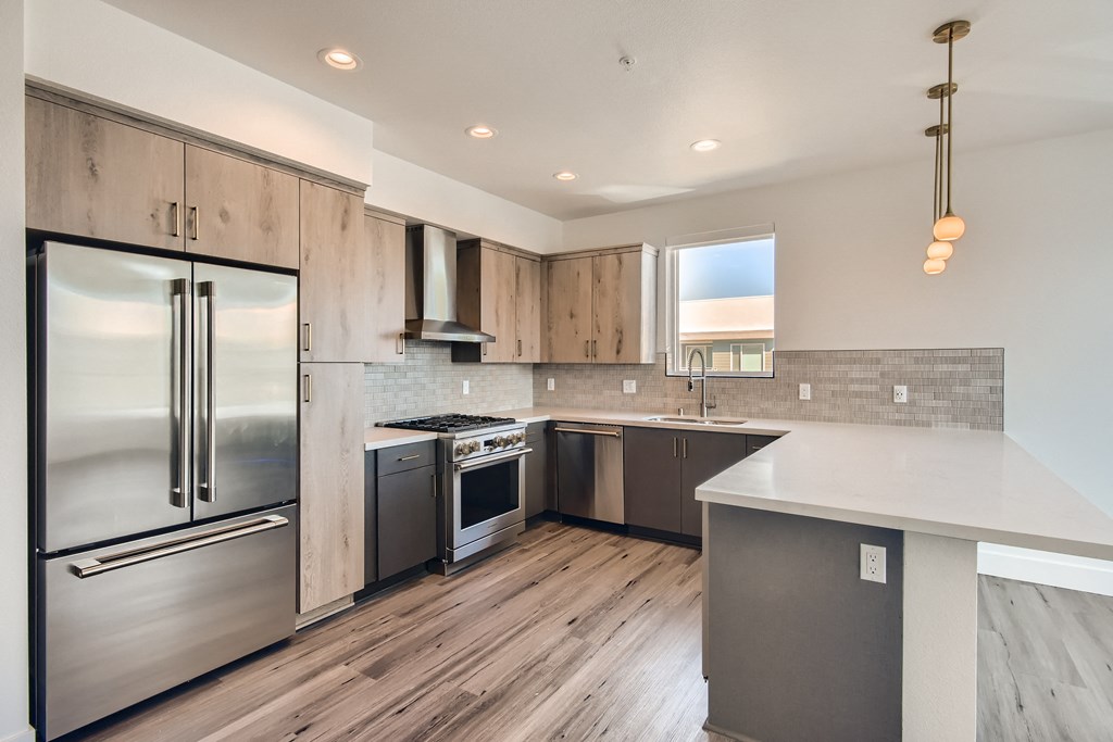A modern kitchen with a stainless steel refrigerator and wooden cabinets.